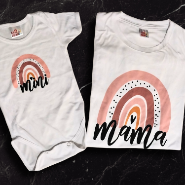 Set de playera blanca para mamá y pañalero (body) para bebé con estampado de arcoíris boho en tonos tierra; diseño cristiano 'Mama' y 'Mini' sobre fondo de mármol negro.